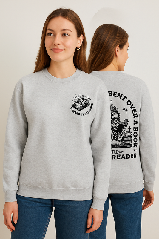 Light gray crewneck sweatshirt featuring bold black bookish graphics. The front chest has a small open-book design with a hand and the phrase “Spread Those Pages.” The back showcases a full skeleton girl reading, surrounded by stacked books, coffee, and sparkles. Large text reads: “I Look Better Bent Over a Book – Proud Smut Reader.” A cozy, cheeky must-have for spicy book lovers with a sense of humor.