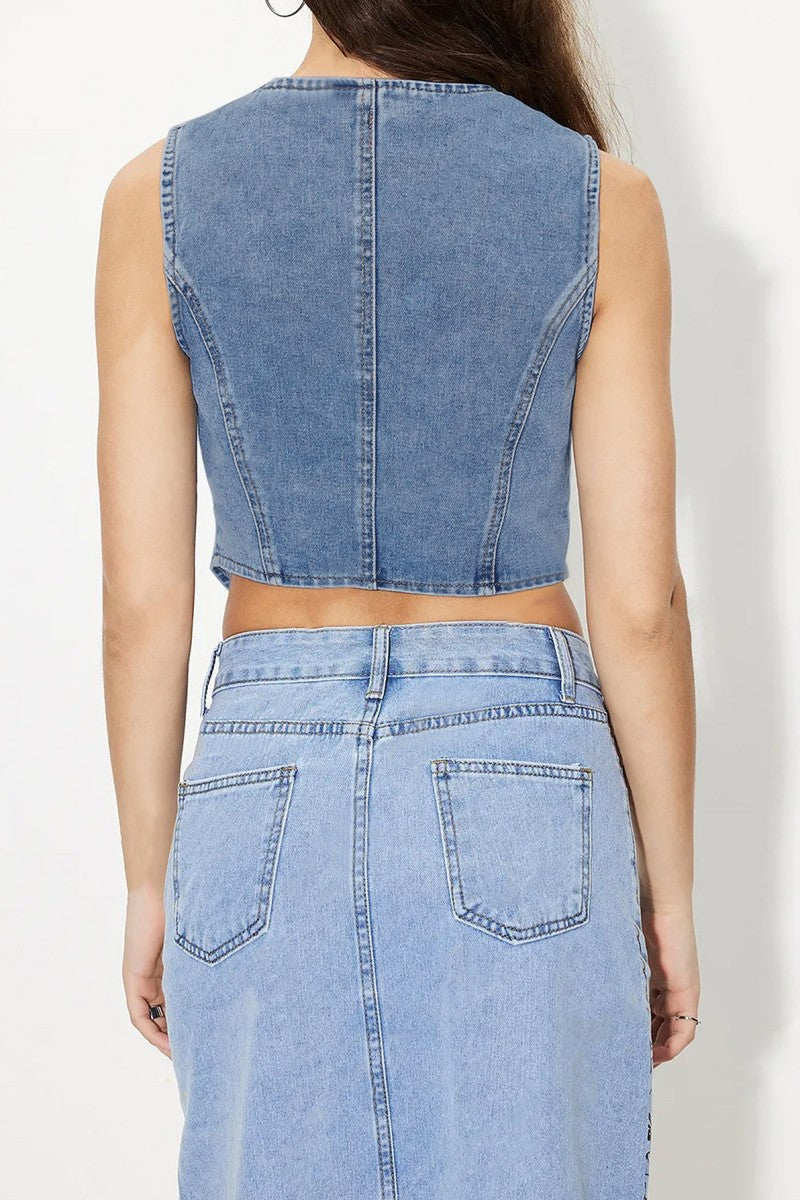 Light wash denim vest top featuring a tailored V-neckline, angled hemline, and asymmetrical button-down front. This sleeveless piece adds a vintage-meets-modern vibe to any outfit and pairs perfectly with high-rise jeans or shorts for an edgy, casual-cool look.