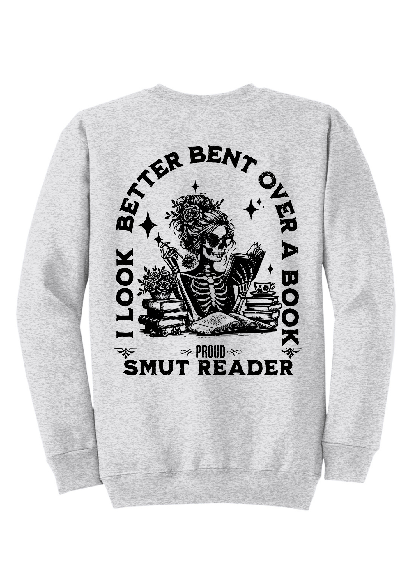 Light gray crewneck sweatshirt featuring bold black bookish graphics. The front chest has a small open-book design with a hand and the phrase “Spread Those Pages.” The back showcases a full skeleton girl reading, surrounded by stacked books, coffee, and sparkles. Large text reads: “I Look Better Bent Over a Book – Proud Smut Reader.” A cozy, cheeky must-have for spicy book lovers with a sense of humor.