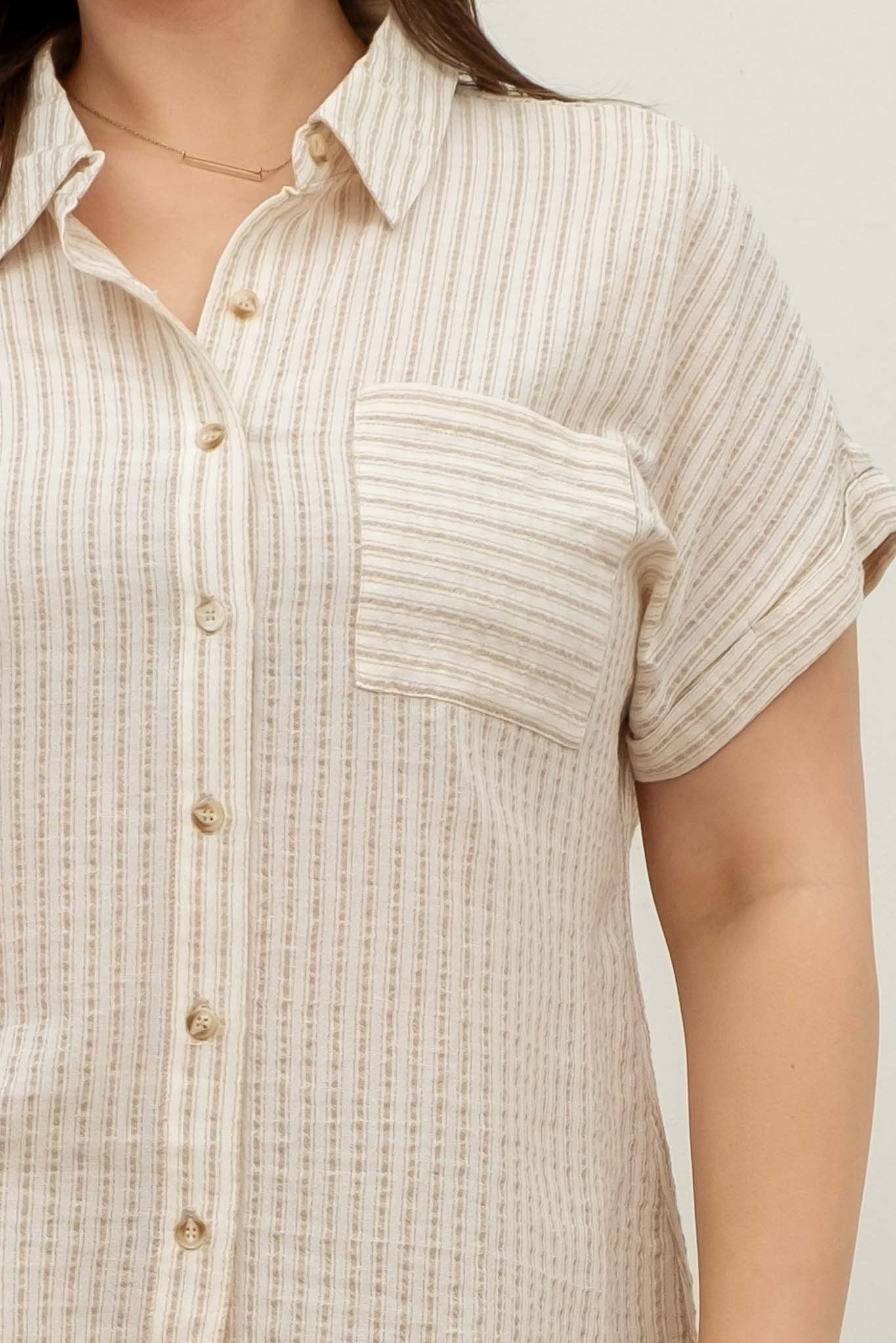 Short-sleeve button-up shirt in a neutral cream and tan stripe pattern, featuring a collared neckline and a chest pocket with horizontal stripe contrast. Lightweight, breathable fabric with a relaxed fit for everyday wear. A versatile top that pairs effortlessly with denim, trousers, or shorts for a casual yet polished look.