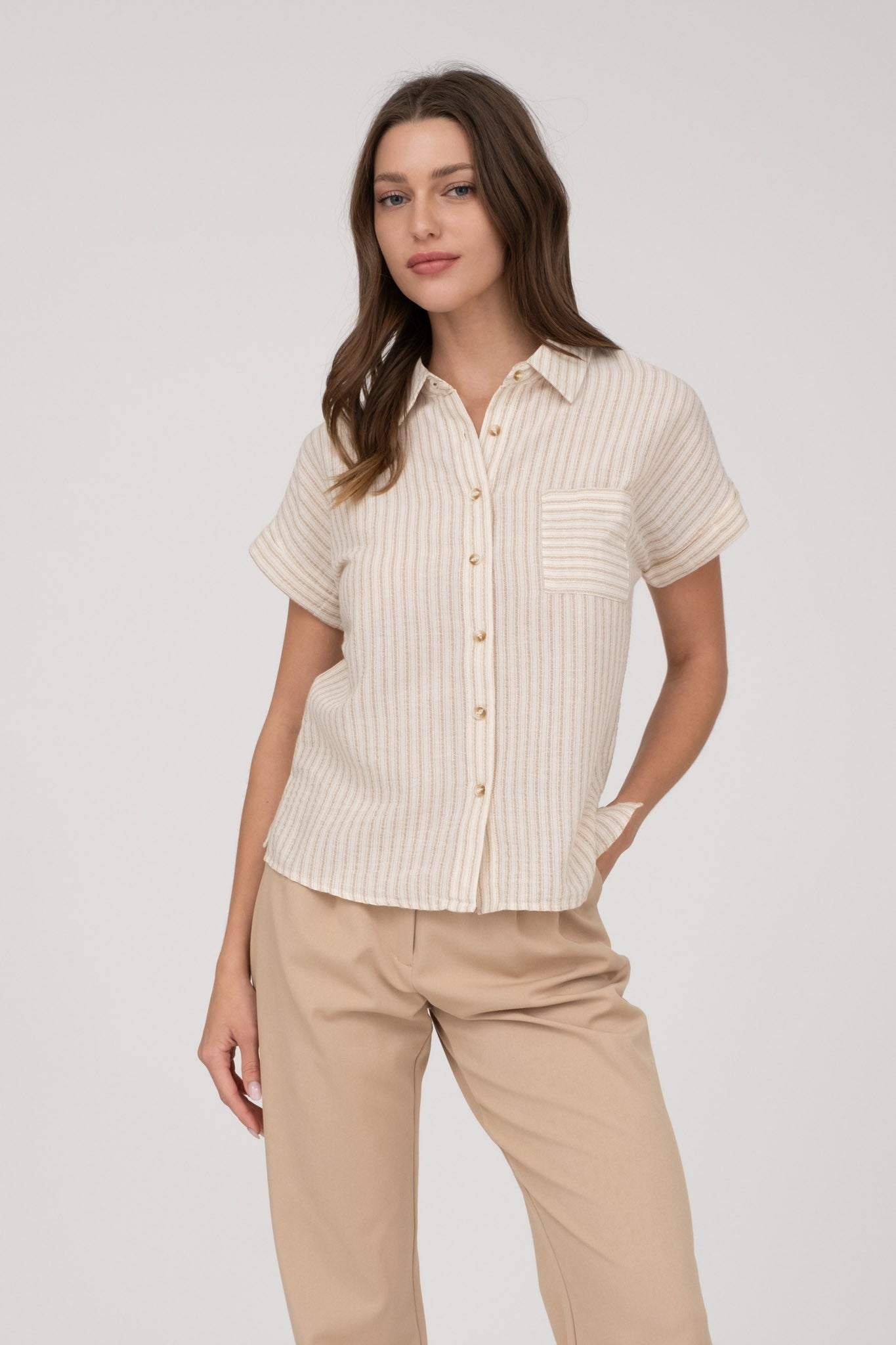 Short-sleeve button-up shirt in a neutral cream and tan stripe pattern, featuring a collared neckline and a chest pocket with horizontal stripe contrast. Lightweight, breathable fabric with a relaxed fit for everyday wear. A versatile top that pairs effortlessly with denim, trousers, or shorts for a casual yet polished look.