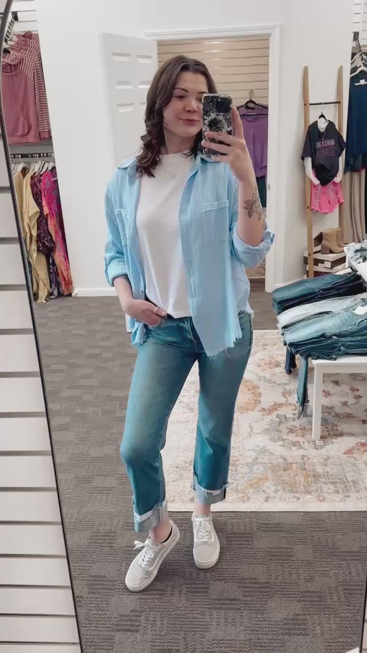 Lightweight and breezy button-down shirt in a soft, crinkled gauze fabric, featured in a fresh Spring Blue. Designed with dual chest pockets, raw-edge hem, and rolled long sleeves with button tabs. Slightly oversized fit for easy layering over tanks, tees, or swimsuits—perfect for casual days, lake life, or cool summer nights.