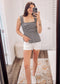 Woman wearing a black and white striped smocked peplum tank top with wide ruffled straps and a square neckline. The fitted smocked bodice creates a flattering silhouette, flaring into a flowy hem. Paired with light beige distressed denim shorts featuring frayed edges, this look is playful and breezy—perfect for sunny days, beach outings, or casual summer hangouts.