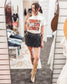 Beige graphic tee featuring a bold red "Tears of a Cowboy" slogan layered over a black-and-white rodeo newspaper print. Accents include dice, a horseshoe, and distressed lettering for an edgy Western-meets-streetwear vibe. Perfect for rodeo rebels, heartbreak cowgirls, or anyone living on the wild side of the saddle.