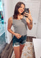 Woman wearing a casual sleeveless tank top with horizontal forest green and white stripes. The top features a scoop neckline and a relaxed, slightly flared silhouette that offers a breezy, comfortable fit. Styled with distressed dark-wash denim shorts, this easygoing look is perfect for everyday wear, beach days, or layering under summer cardigans and jackets.