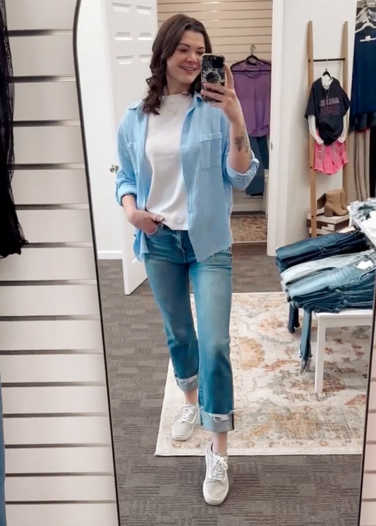 Lightweight and breezy button-down shirt in a soft, crinkled gauze fabric, featured in a fresh Spring Blue. Designed with dual chest pockets, raw-edge hem, and rolled long sleeves with button tabs. Slightly oversized fit for easy layering over tanks, tees, or swimsuits—perfect for casual days, lake life, or cool summer nights.