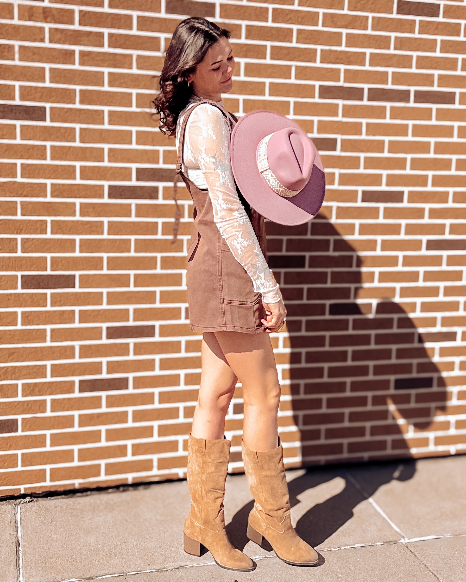 Sleeveless mahogany overall-style dress with a soft, washed finish and relaxed silhouette. Features a deep V-neckline, wide shoulder straps with tie-back detail, and oversized front patch pockets. Slightly A-line cut with above-the-knee hem for easy, breezy styling. Perfect for layering over tanks or bralettes for a casual, warm-weather look.
