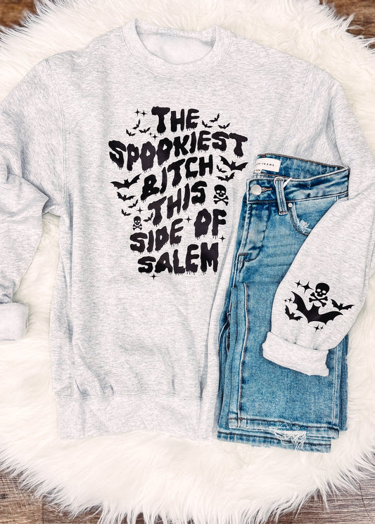 Gray sweatshirt with text and denim jacket on a fluffy white rug