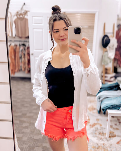 Women's oversized button-down gauze shirt in crisp white, featuring a textured crinkle fabric with a soft, breathable feel. Designed with a front chest pocket, raw-edge hemline, and functional silver snap buttons. Long sleeves with drop shoulders and a relaxed fit for effortless layering over tanks or tees. Lightweight yet cozy—perfect for tossing on during breezy summer nights or early fall mornings.