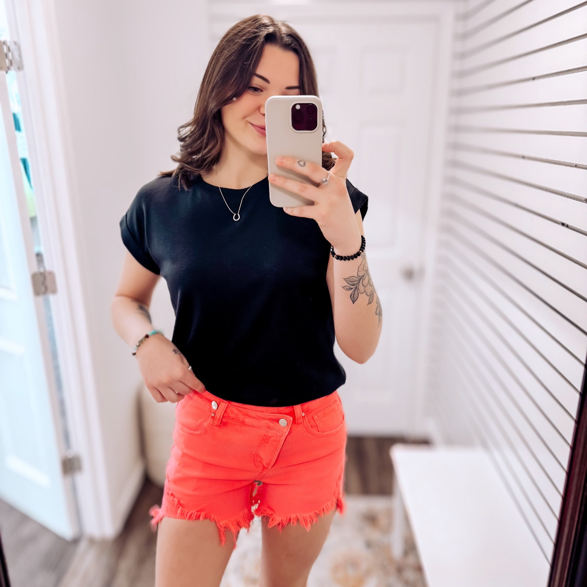 High-rise neon coral denim shorts with bold distressing and frayed hems. These eye-catching cutoffs feature a raw edge, angled hemline, and subtle peek-through front distressing for added flair. Designed with a crossover waistband and classic five-pocket construction. Perfect for adding a vibrant pop to your summer wardrobe—style with graphic tanks or breezy tees for a fun, playful look.