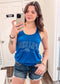 Woman wearing a royal blue racerback tank top with bold white lettering that reads “LAKE LIFE” across the chest and “is the best life” underneath with a small sun graphic. The tank has a relaxed fit and a soft, stretchy fabric, perfect for warm weather and laid-back summer days. She pairs it with dark-wash, frayed denim shorts for a casual, outdoorsy vibe ideal for weekends at the lake, boating, or bonfires.