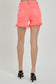 High-rise neon coral denim shorts with bold distressing and frayed hems. These eye-catching cutoffs feature a raw edge, angled hemline, and subtle peek-through front distressing for added flair. Designed with a crossover waistband and classic five-pocket construction. Perfect for adding a vibrant pop to your summer wardrobe—style with graphic tanks or breezy tees for a fun, playful look.