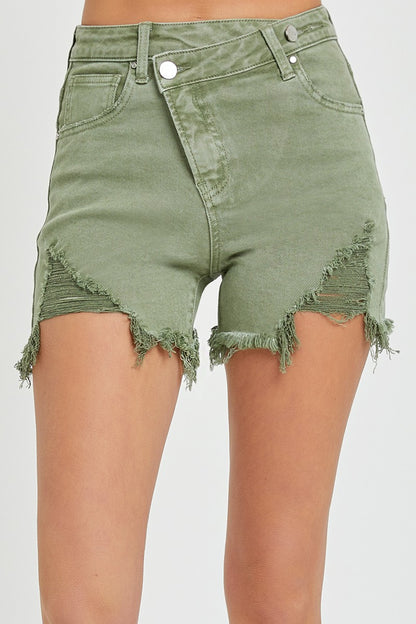 High-rise olive denim shorts with edgy angled hems and heavy distressing on the front thighs. Designed with a raw, frayed finish and exposed pocket lining for a laid-back, worn-in vibe. Features a zip fly with double-button closure and classic five-pocket styling. A bold twist on your go-to cutoffs—perfect for pairing with tanks, graphic tees, or festival fits.