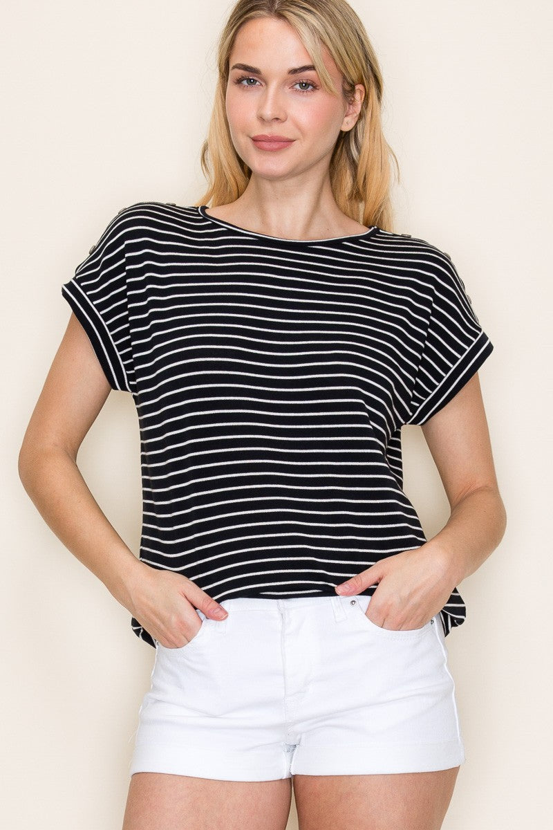 Woman wearing a black short-sleeve top with thin white horizontal stripes, a classic crew neckline, and rolled cuff sleeves with button accents. The top features a relaxed, drapey fit that pairs effortlessly with white cuffed shorts for a crisp, casual look. Perfect for everyday wear, this lightweight striped tee brings timeless style and comfort to your summer wardrobe.