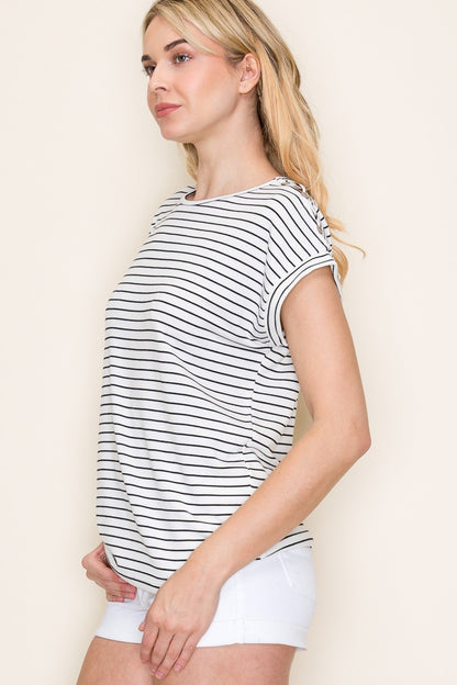 Woman wearing a white short-sleeve top with thin black horizontal stripes and rolled cuffs. The shirt features a relaxed, flowy fit with a crew neckline and button detail on the sleeves. Styled with white cuffed shorts, this effortless everyday tee is perfect for warm weather, offering a classic nautical-inspired look that’s both casual and polished.