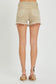 High-rise tan denim shorts with a perfectly lived-in look, featuring heavy distressing along the raw hem and side slits for extra edge. Classic five-pocket design with frayed detailing at the waistband and front pockets. These neutral cutoffs are easy to pair with any summer tank or graphic tee, making them a go-to for lake days, festivals, or backyard hangs.