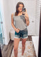 Woman wearing a casual sleeveless tank top with horizontal forest green and white stripes. The top features a scoop neckline and a relaxed, slightly flared silhouette that offers a breezy, comfortable fit. Styled with distressed dark-wash denim shorts, this easygoing look is perfect for everyday wear, beach days, or layering under summer cardigans and jackets.