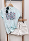 Light blue unisex t-shirt featuring bold "USA" block letters filled with a red, white, and blue floral pattern for a faux-embroidered look. Below, "EST. 1776" is printed in navy with red stars, celebrating American heritage. Classic crew neck and short sleeves offer a comfortable fit, perfect for patriotic holidays like the Fourth of July or Memorial Day.