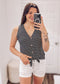 Woman wearing a sleeveless black and white horizontal striped tank top with a deep V-neckline and functional wooden buttons down the front. The top features a trendy front tie detail at the hem, creating a casual, flattering silhouette. Made from a soft, lightweight fabric, it's styled with medium-wash denim jeans—perfect for laid-back summer days, weekend outings, or everyday wear.