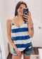 Woman wearing a blue and white striped tank top with a breezy, relaxed fit. The sleeveless top features bold horizontal stripes, a deep V-neckline, and contrasting aqua trim along the neckline and spaghetti straps. Lightweight and easygoing, this tank is paired with light-wash distressed denim shorts—perfect for summer days, beach trips, or casual outings with a fun pop of color.