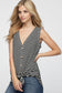 Woman wearing a sleeveless black and white horizontal striped tank top with a deep V-neckline and functional wooden buttons down the front. The top features a trendy front tie detail at the hem, creating a casual, flattering silhouette. Made from a soft, lightweight fabric, it's styled with medium-wash denim jeans—perfect for laid-back summer days, weekend outings, or everyday wear.