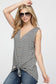 Woman wearing a sleeveless black and white horizontal striped tank top with a deep V-neckline and functional wooden buttons down the front. The top features a trendy front tie detail at the hem, creating a casual, flattering silhouette. Made from a soft, lightweight fabric, it's styled with medium-wash denim jeans—perfect for laid-back summer days, weekend outings, or everyday wear.