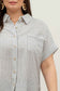 model wearing a short-sleeve button-up top with vertical black and white pinstripes. Features a collared neckline, front chest pocket with horizontal stripes for contrast, and a relaxed, slightly oversized fit. The shirt is styled with a black denim mini skirt, creating an effortlessly chic and casual look perfect for everyday wear