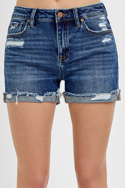 Medium-wash denim shorts featuring a mid-rise fit, cuffed raw hem, and distressed details throughout the front and pockets. These shorts blend laid-back edge with everyday comfort thanks to the soft stretch denim and versatile length. The perfect pair for casual summer days, music festivals, or throwing on over a swimsuit.