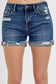 Medium-wash denim shorts featuring a mid-rise fit, cuffed raw hem, and distressed details throughout the front and pockets. These shorts blend laid-back edge with everyday comfort thanks to the soft stretch denim and versatile length. The perfect pair for casual summer days, music festivals, or throwing on over a swimsuit.