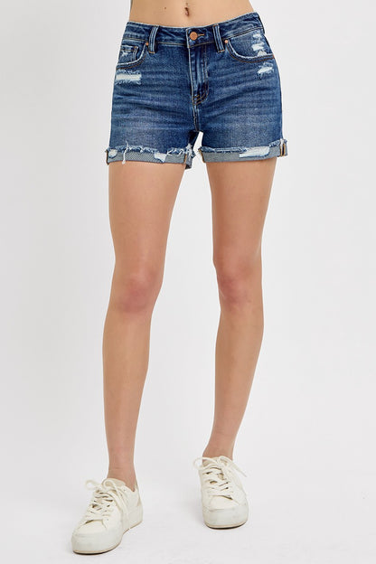 Medium-wash denim shorts featuring a mid-rise fit, cuffed raw hem, and distressed details throughout the front and pockets. These shorts blend laid-back edge with everyday comfort thanks to the soft stretch denim and versatile length. The perfect pair for casual summer days, music festivals, or throwing on over a swimsuit.