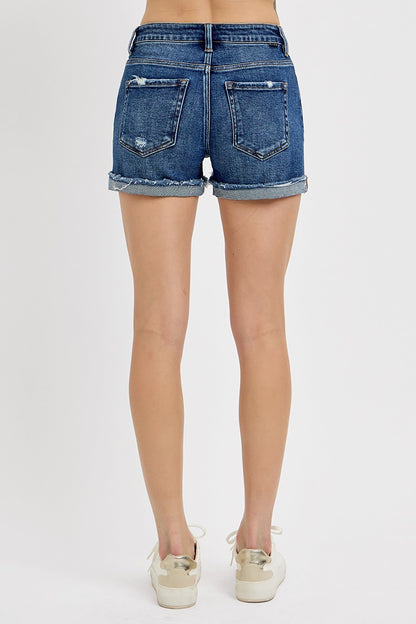 Medium-wash denim shorts featuring a mid-rise fit, cuffed raw hem, and distressed details throughout the front and pockets. These shorts blend laid-back edge with everyday comfort thanks to the soft stretch denim and versatile length. The perfect pair for casual summer days, music festivals, or throwing on over a swimsuit.