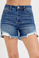 High-rise medium-wash denim shorts featuring a raw frayed hem with peekaboo white lining and light distressing along the edges. Designed with a classic five-pocket style and a flattering fit through the hips and thighs. These shorts are a laid-back summer staple—perfect for pairing with tanks, crop tops, or graphic tees for an effortlessly cool vibe