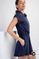Navy short sleeve romper with a sporty polo-style collar and quarter zip neckline. Features an elastic waistband for a flattering fit and a flowy skirted bottom that offers both movement and comfort. Made from recycled polyester for an eco-conscious touch. A versatile one-piece perfect for active days, travel, or casual outings.