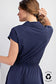 Navy short sleeve romper with a sporty polo-style collar and quarter zip neckline. Features an elastic waistband for a flattering fit and a flowy skirted bottom that offers both movement and comfort. Made from recycled polyester for an eco-conscious touch. A versatile one-piece perfect for active days, travel, or casual outings.