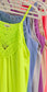 Woman taking a mirror selfie wearing a neon yellow sleeveless halter tank top with intricate crochet lace detailing along the neckline and chest. The flowy, lightweight fabric offers a relaxed fit, perfect for summer. She pairs it with medium-wash denim shorts. The vibrant color and breezy design make it an eye-catching, warm-weather staple.