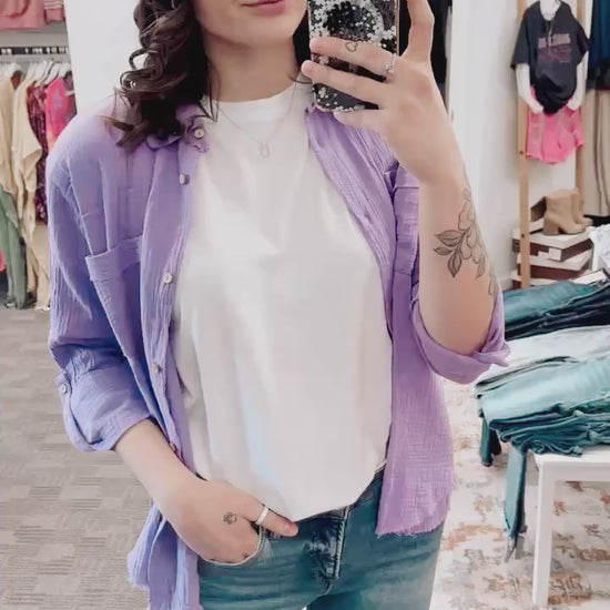 Textured lavender button-down shirt with a relaxed, oversized fit and lightweight gauze fabric. Features raw-edge hems, double chest pockets, wood-look buttons, and roll-tab sleeves. A breezy, versatile layer for spring and summer that pairs effortlessly with denim, tanks, or swimwear.