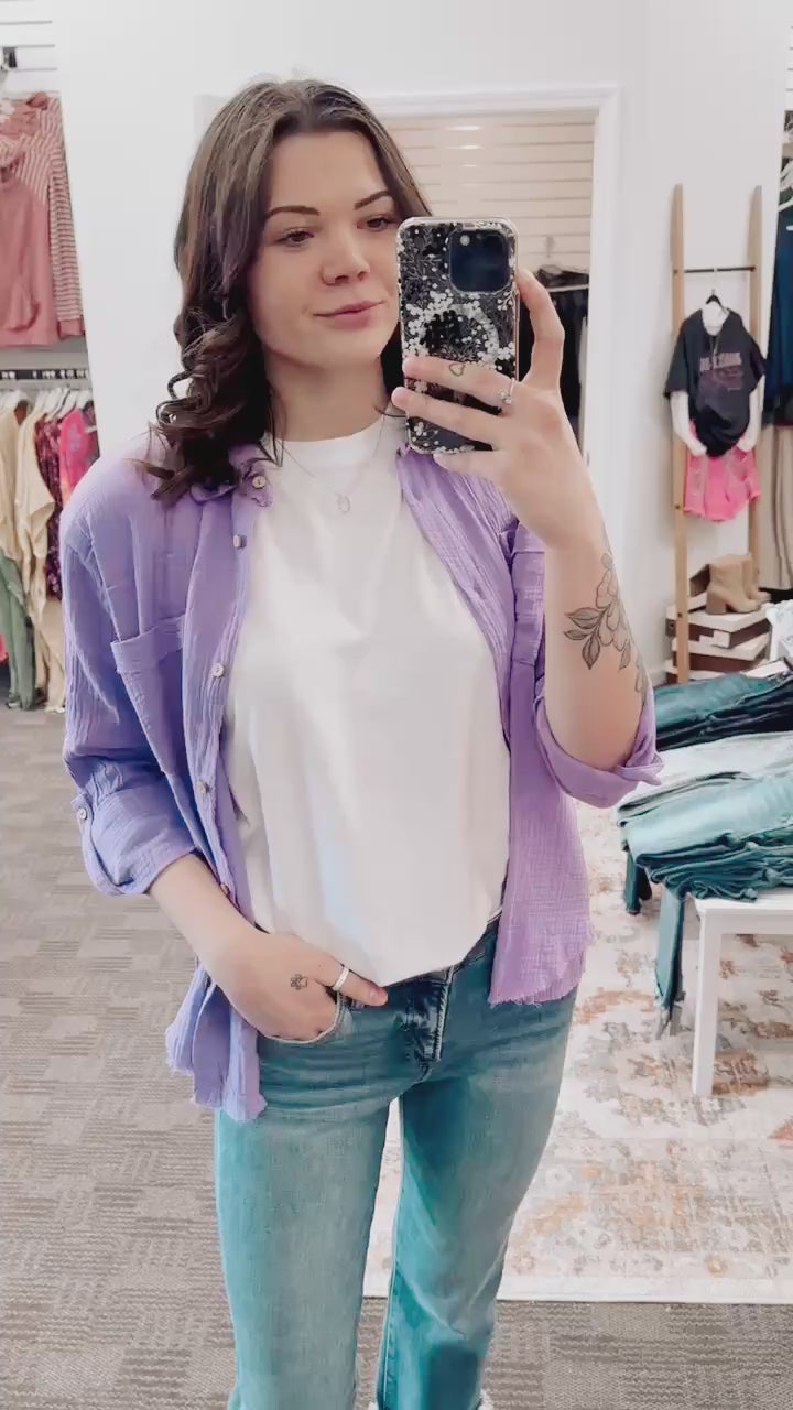 Textured lavender button-down shirt with a relaxed, oversized fit and lightweight gauze fabric. Features raw-edge hems, double chest pockets, wood-look buttons, and roll-tab sleeves. A breezy, versatile layer for spring and summer that pairs effortlessly with denim, tanks, or swimwear.